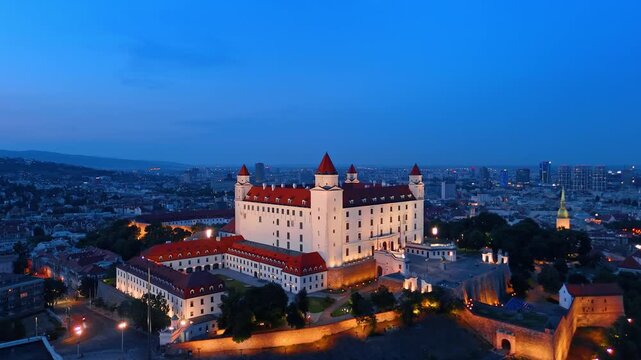 Aerial view of Bratislava castle courtyard at night, Slovakia. Close overhead shot of illuminated palace complex and cathedral spire.