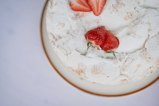 Meringue cream cake with strawberries and powdered sugar
