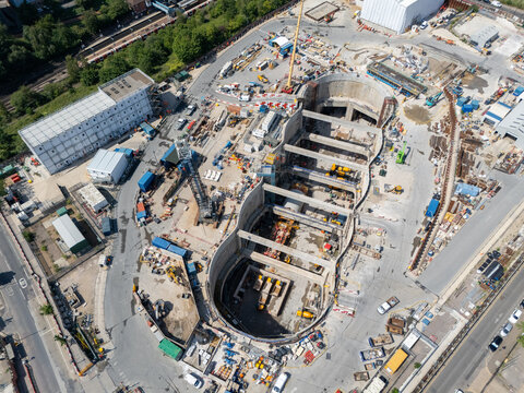 Aerial view of the Old Oak Common station HS2 construction site, featuring deep excavation pits, heavy machinery, cranes, and temporary site structures in London, England, United Kingdom.