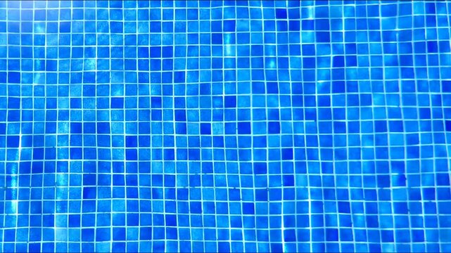 Ripples on water in sunlight over bright blue tile mosaic bottom at swimming pool