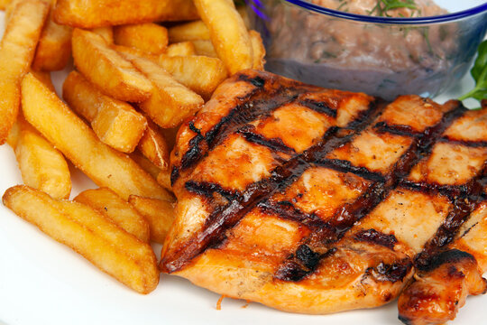 Closeups of a grilled chicken or pork neck steak served with crispy golden french fries. Barbecue meat dish, hot dinner food meal, savory restaurant culinary catering. BBQ.