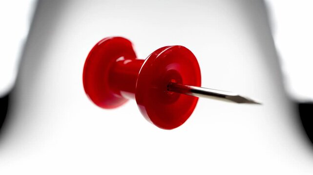 Red pushpin spinning against white background
