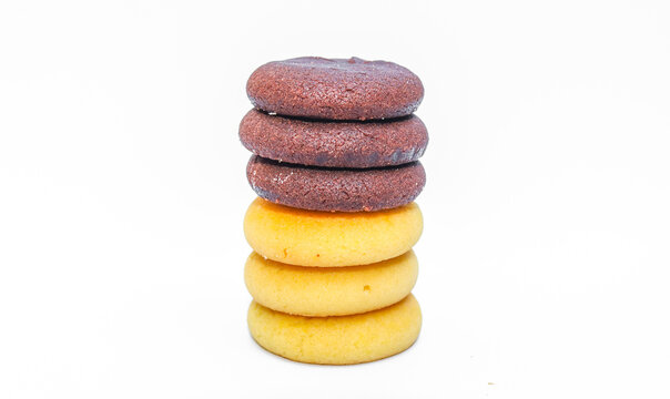 Assorted chocolate cookies and pineapple jam filled cookies isolated on white background. Brown and golden round biscuits arranged in a stack