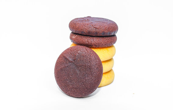 Assorted chocolate cookies and pineapple jam filled cookies isolated on white background. Brown and golden round biscuits arranged in a stack