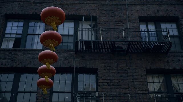 Line Of Red Lanterns Attached to Brick Building In San Francisco's Chinatown At Dusk