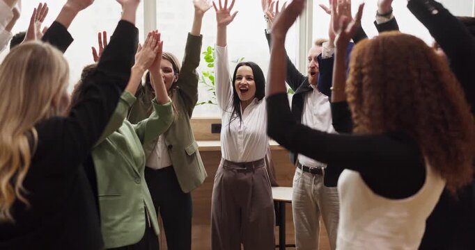 Business team colleagues in office cheering victory. Coworkers raise hands and applaud after reaching a milestone, showing unity and motivation. Energetic teamwork celebration and success.