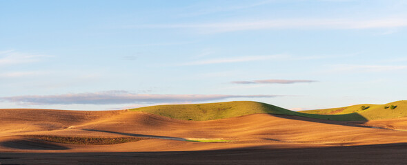 Fototapeta premium dirt fields with rolling hills with light on the hill