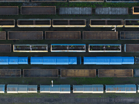 Aerial view of trainyard with rows of freight train cars, including blue covered wagons and open cargo containers, on parallel tracks in Krakow, Lesser Poland Voivodeship, Poland.