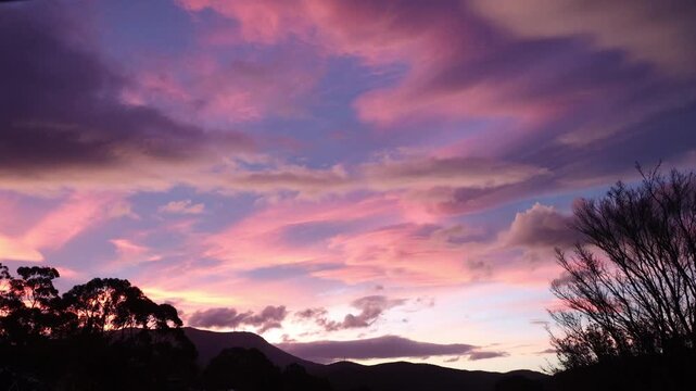 timelapse of beautiful sunset with pink clouds over tasmanian mountains transitioning into twilight, authentic unedited colors in a serene australian landscape scene with dramatic sky and cloud moveme