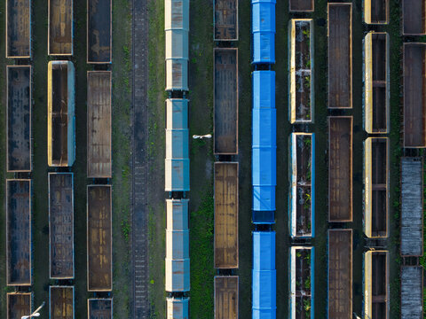 Aerial view of a trainyard with rows of freight train cars, including blue and brown wagons, arranged on parallel tracks in Krakow, Lesser Poland Voivode, Poland.