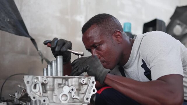 Auto mechanic repairing and assembling car engine cylinder head in workshop, Skilled technician performing engine overhaul and maintenance service using a socket wrench