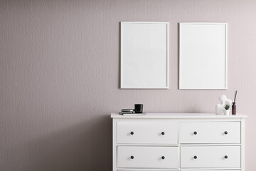 Fototapeta premium Minimalist interior with white dresser and blank frames