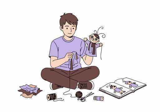 Young man sitting cross legged and crafting a handmade puppet