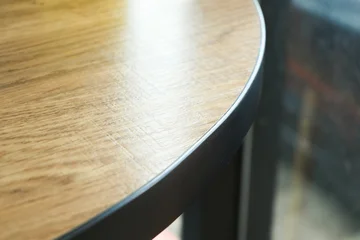 close up detail of a round wooden tabletop with black metal edge © sutichak