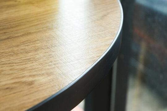 close up detail of a round wooden tabletop with black metal edge