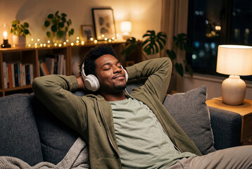 Fototapeta premium Relaxed young black man listening to music on a sofa