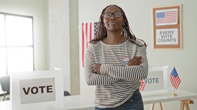 Woman stands with arms crossed beside ballot box and vote sign in a building, wearing an i voted sticker and glasses; civic duty pride.