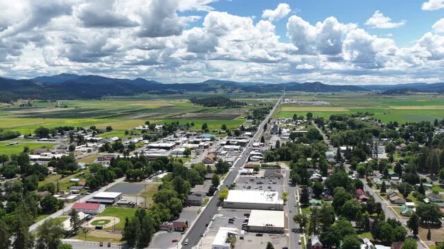 Aerial of small town center and farmland in Chewelah Washington with main commercial street and residential neighborhoods in summer