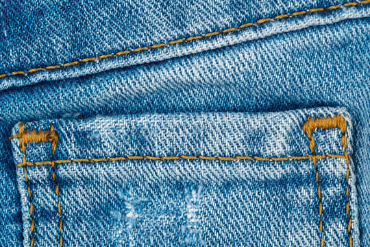 Blue denim texture with classic orange stitching and back pocket detail