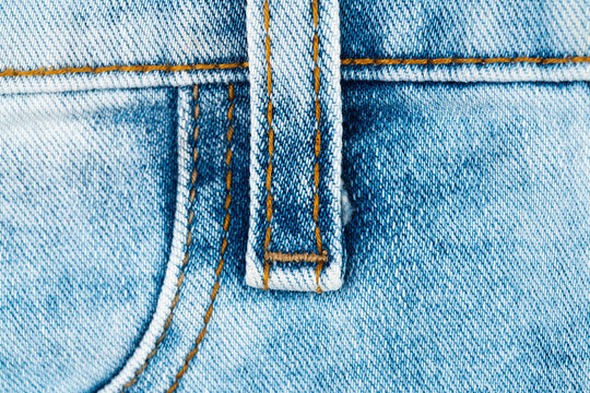 Closeup of blue denim jeans with orange stitching and belt loop