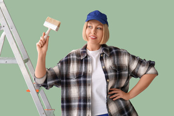 Naklejka premium Female decorator with ladder and brush on green background