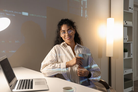 Female African-American programmer working with clipboard in office at night