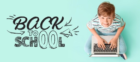 Smiling boy using laptop with back to school text © Pixel-Shot
