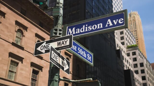 Street-level view of the Madison Avenue and East 50th Street intersection in Midtown Manhattan, capturing iconic New York City signage and the energy of the surrounding urban landscape.