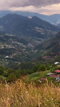 Mountain range of Caucasus and rural village countryside of Khulo town highland Georgia rustic vertical serene landscape wooden cabin steep green slope forest grazing alpine meadows valley wilderness