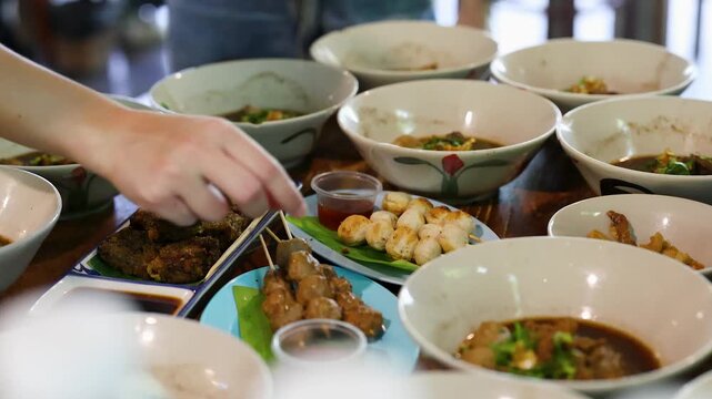 Traditional Thai Boat Noodles and Grilled Meatball Skewers on Restaurant Table
