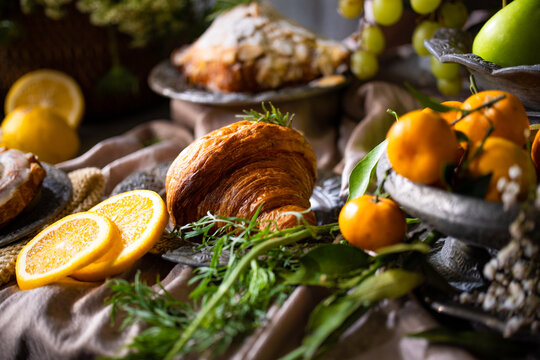 Elegant gourmet breakfast still life featuring fresh fruits, pastries, and rustic tableware arranged in a luxurious artistic composition