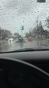 Vehicle driving through a yellow traffic light on a rainy day, view from inside the car