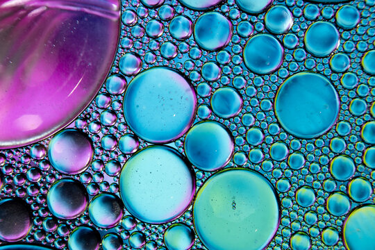 Large and small floating oil bubbles create an abstract visual texture in the water.