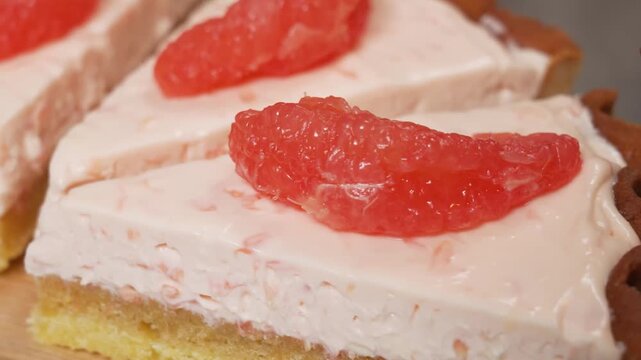 footage of two delicious slices of pink grapefruit cream pie. The dessert features a buttery crust, a smooth creamy pink mousse layer, and is topped with fresh, juicy ruby red grapefruit segments. Per