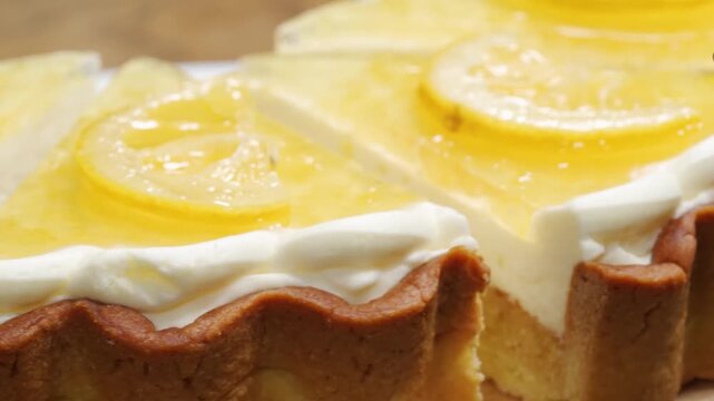 close-up shot of delicious homemade lemon tart slices featuring a rich, yellow citrus curd filling and a fluted golden-brown pastry crust. The dessert is elegantly topped with a swirl of fresh white w