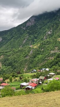 Rural village and meadow countryside landscape of mountain people hills life on green field hay bale aerial panoramic Caucasus Georgia Khulo Borjomi summer cloudy pine forest valley riverside scenic