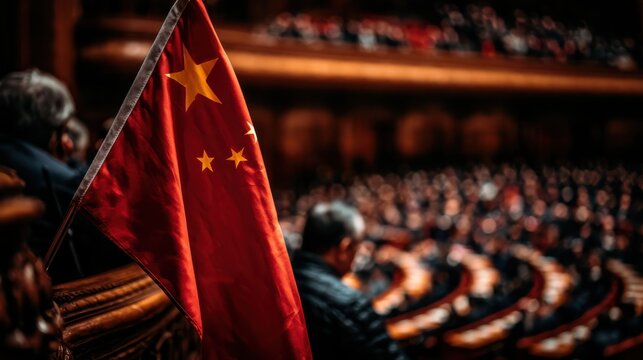 A Chinese flag is prominently displayed in a dimly lit assembly or legislative chamber filled with seated people.