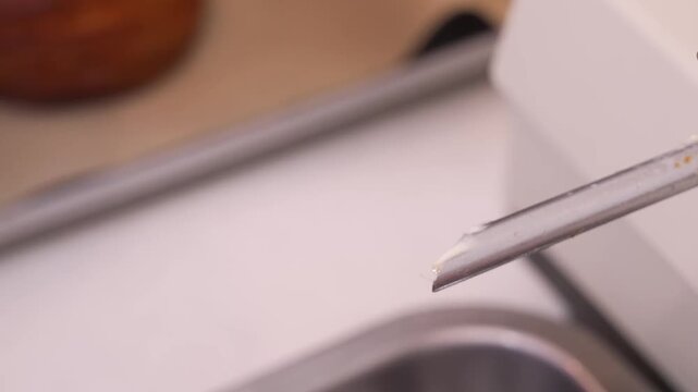 Close-up footage of a professional pastry chef using a metal nozzle to inject a creamy sweet filling into a freshly baked, golden-brown flaky puff pastry. The shot highlights the crispy texture and th