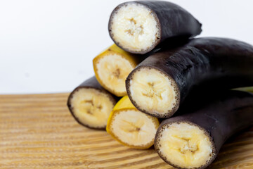 Close-up of cut yellow and dark bananas stacked on a wooden board, showing contrast between ripe and overripe fruit  © Natalya Likhina