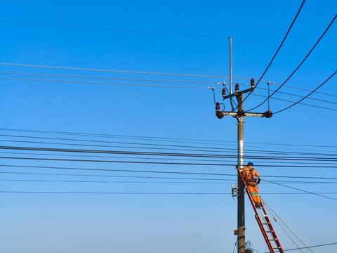 a worker repairing power lines on a utility pole