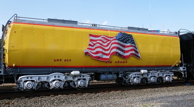 Pottstown, Pennsylvania, U.S.A - Jul 2, 2026 - Yellow UPP 809 tender labeled Jim Adams with large American flag graphic and silver undercarriage.