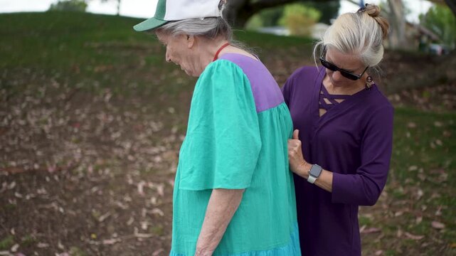 Happy daughter spends time massaging her elderly mother on her sore back, helping her relieve pain.