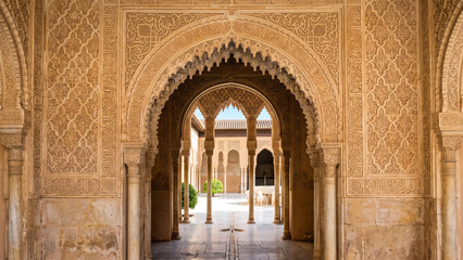 Obraz premium Elegant Andalusian horseshoe arch entrance featuring intricate limestone carvings, traditional Islamic architecture, and timeless Moorish craftsmanship in a historic palace setting.