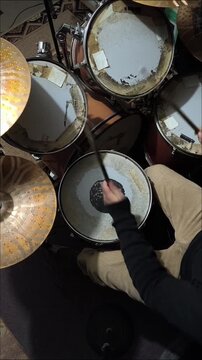 Overhead close up of a musician playing an acoustic drum kit, vertical shot