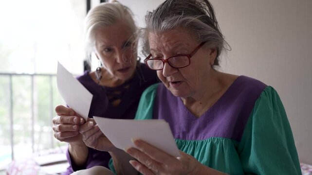 Daughter spends time with her mother at a senior care facility talking and sharing family photos and memories from the past