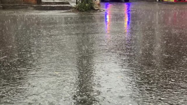 Rainwater droplets splash dynamically onto slick asphalt during a heavy afternoon storm.