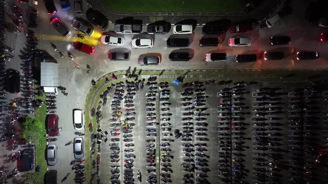 Nighttime aerial view of densely packed motorcycle and car parking lot in Batu Kawan, Malaysia.