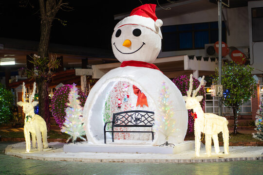 Illuminated snowman Christmas decoration with glowing reindeer and festive holiday lights at night