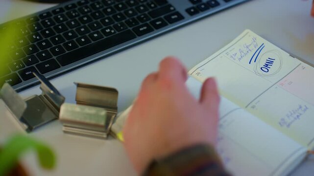 Close-up of a worker marking paperwork beside a computer keyboard during a work task. Useful for office, planning, administration, technical notes and project documentation themes