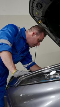Auto Mechanic Examining Electric Vehicle Engine Bay Components